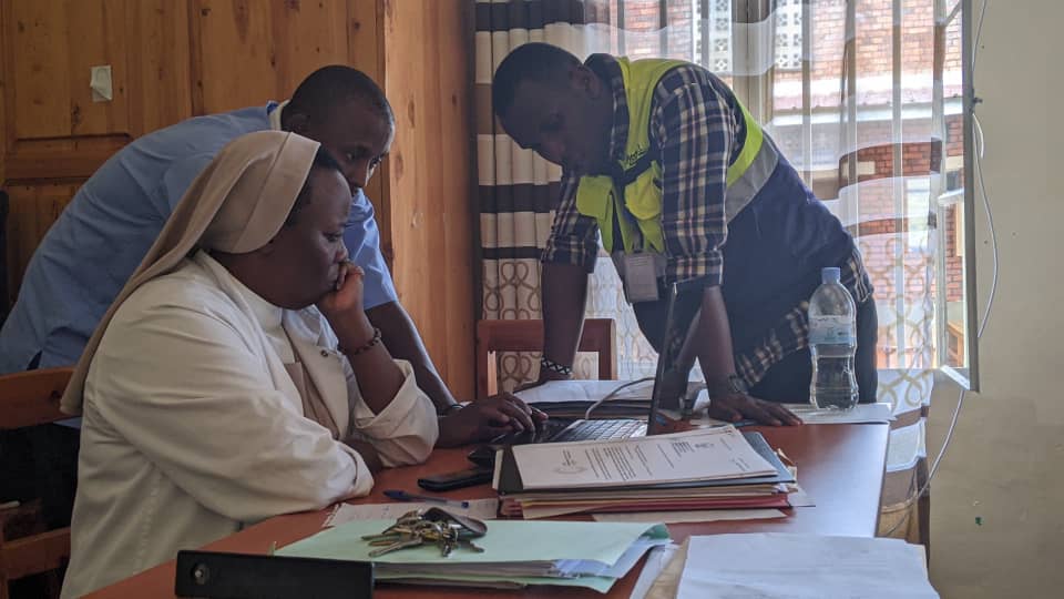 Medisoft trainer in a branded vest doing hands-on training with healthcare staff at a Rwandan facility
